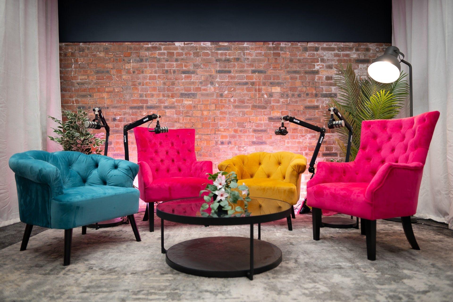 Image showing a podcast studio, complete with 4 coloured armchairs and microphones